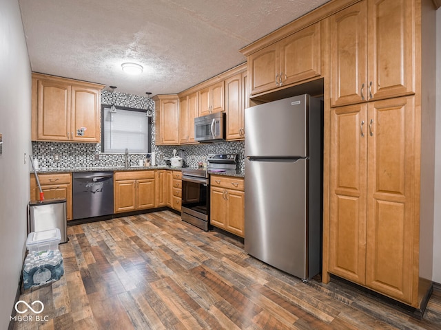 kitchen featuring appliances with stainless steel finishes, dark hardwood / wood-style floors, tasteful backsplash, sink, and a textured ceiling