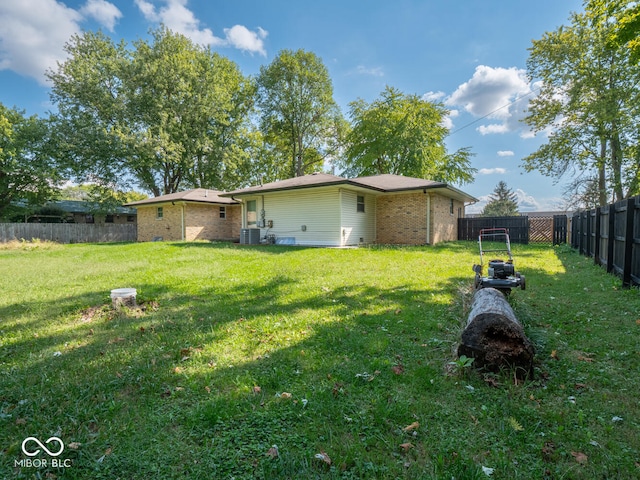 rear view of property featuring a yard and central air condition unit