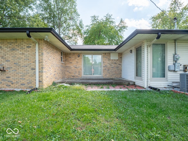 doorway to property with central AC unit and a lawn