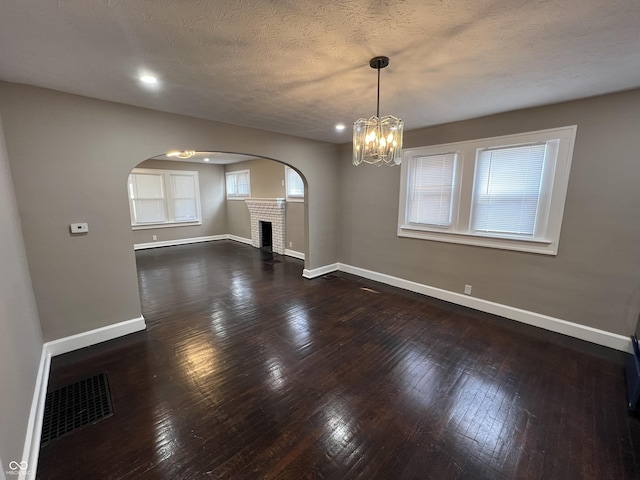 unfurnished room featuring visible vents, baseboards, dark wood finished floors, a chandelier, and arched walkways