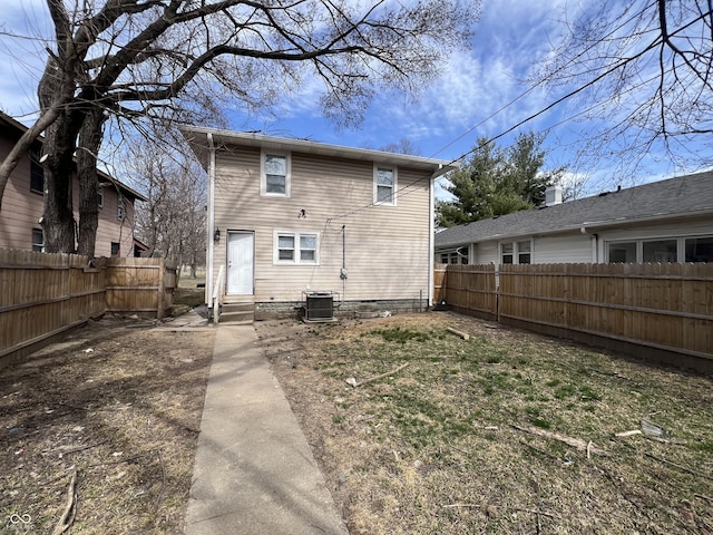 rear view of property featuring cooling unit, entry steps, and a fenced backyard