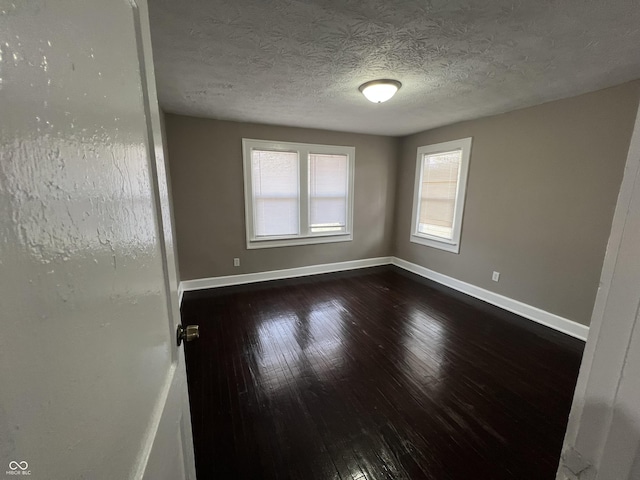 unfurnished room featuring dark wood-type flooring, baseboards, and a textured ceiling