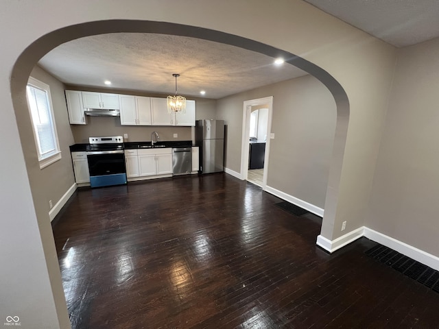 kitchen with under cabinet range hood, appliances with stainless steel finishes, baseboards, and a sink
