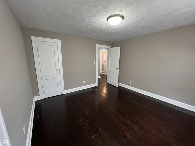 unfurnished bedroom with dark wood finished floors, a textured ceiling, and baseboards