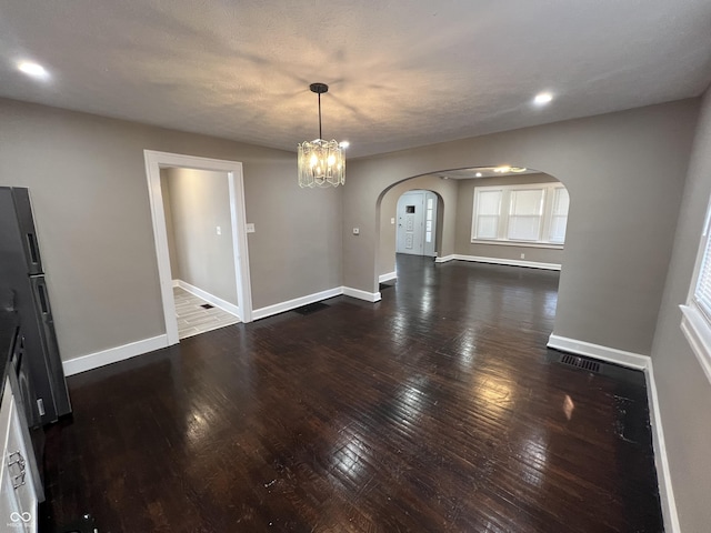 interior space featuring baseboards, recessed lighting, arched walkways, hardwood / wood-style flooring, and a chandelier