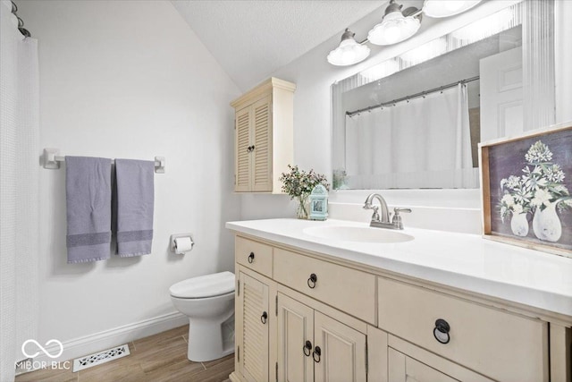 bathroom featuring lofted ceiling, visible vents, toilet, vanity, and wood finished floors