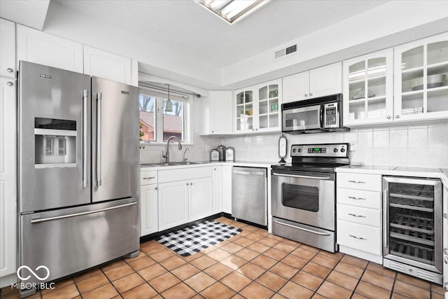 kitchen featuring beverage cooler, a sink, visible vents, light countertops, and appliances with stainless steel finishes