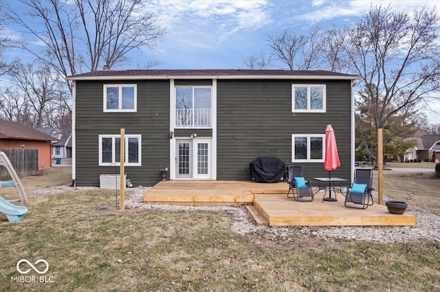 back of house featuring a yard, a playground, a wooden deck, and a balcony