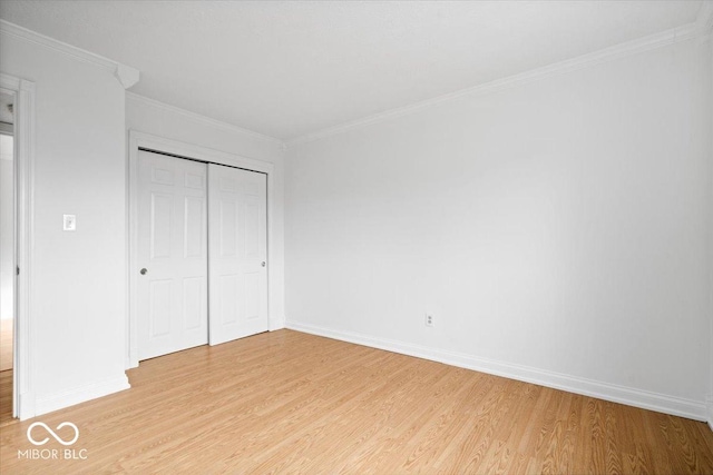 unfurnished bedroom with ornamental molding, light wood-type flooring, a closet, and baseboards