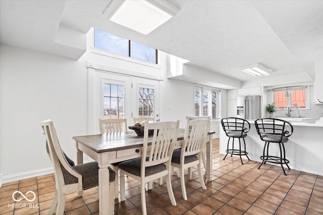 dining area featuring a textured ceiling, baseboards, and light tile patterned floors