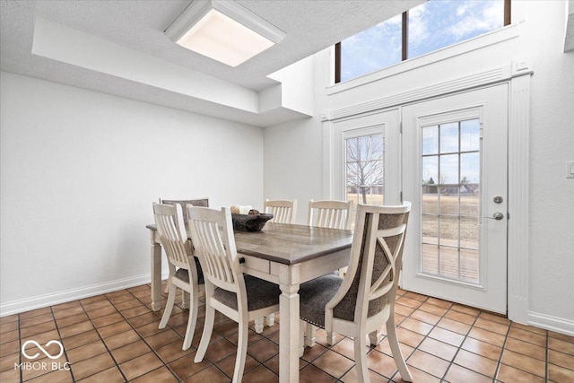 dining space with a textured ceiling, baseboards, and light tile patterned floors