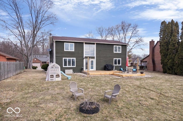 rear view of property with an outdoor fire pit, fence, a lawn, a wooden deck, and a chimney