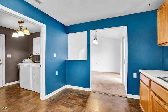 kitchen featuring pendant lighting, baseboards, light countertops, washer and clothes dryer, and an inviting chandelier