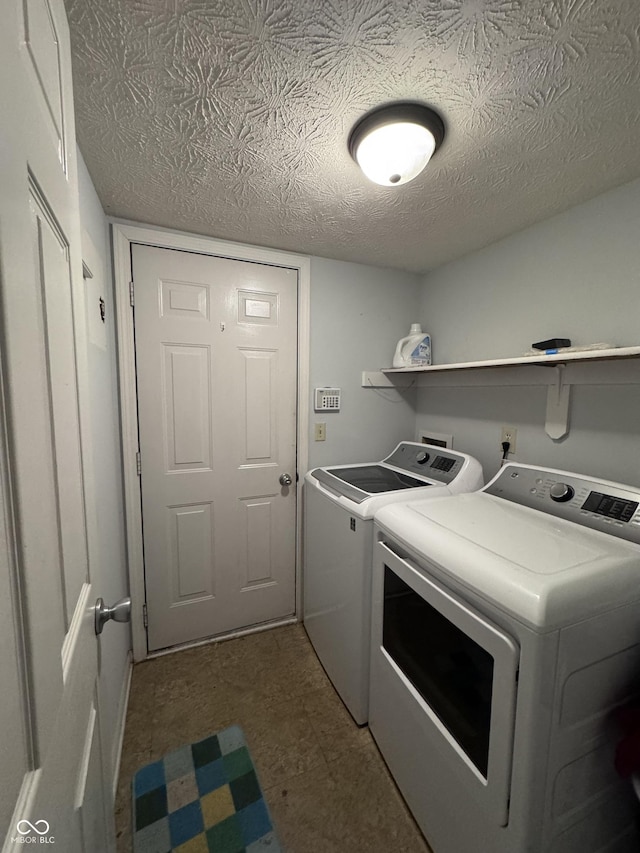 laundry area featuring washing machine and clothes dryer, laundry area, and a textured ceiling