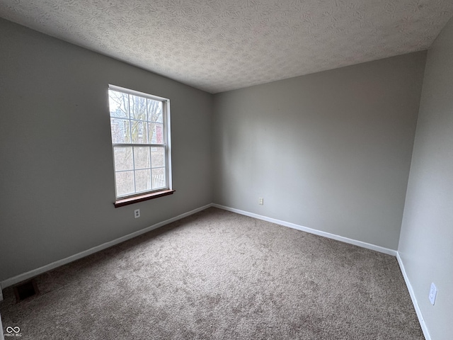 empty room featuring carpet flooring, baseboards, visible vents, and a textured ceiling