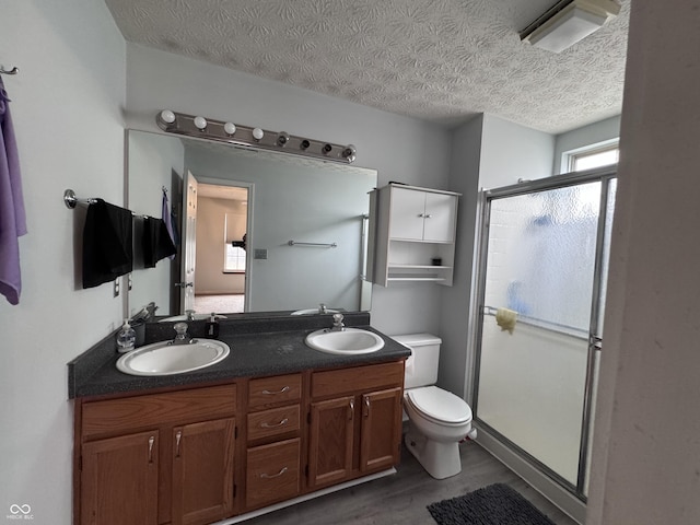 bathroom with a sink, a shower stall, toilet, and double vanity