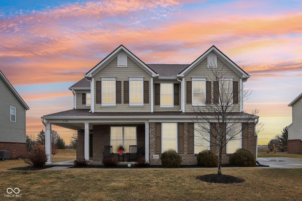 front facade with a yard and covered porch