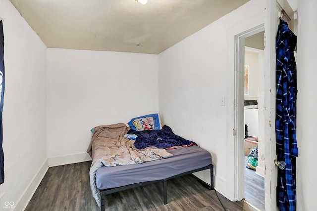 bedroom with washer / dryer and dark hardwood / wood-style flooring