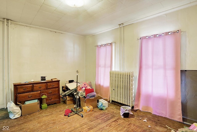 bedroom with ornamental molding, radiator heating unit, and hardwood / wood-style floors