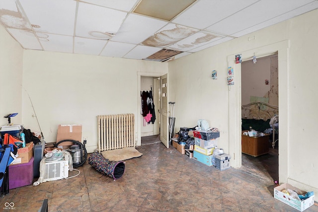 interior space with a paneled ceiling and radiator heating unit