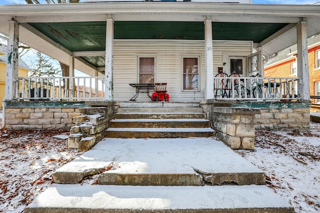 snow covered property entrance featuring covered porch