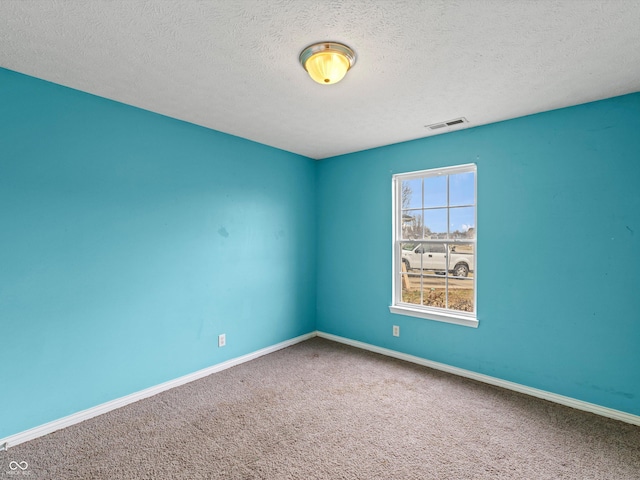 carpeted spare room with baseboards, visible vents, and a textured ceiling