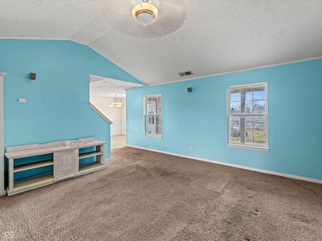 unfurnished living room with carpet floors, visible vents, vaulted ceiling, a textured ceiling, and a chandelier