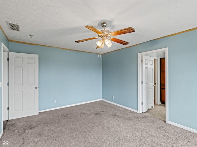 unfurnished room with light colored carpet, visible vents, crown molding, and a textured ceiling