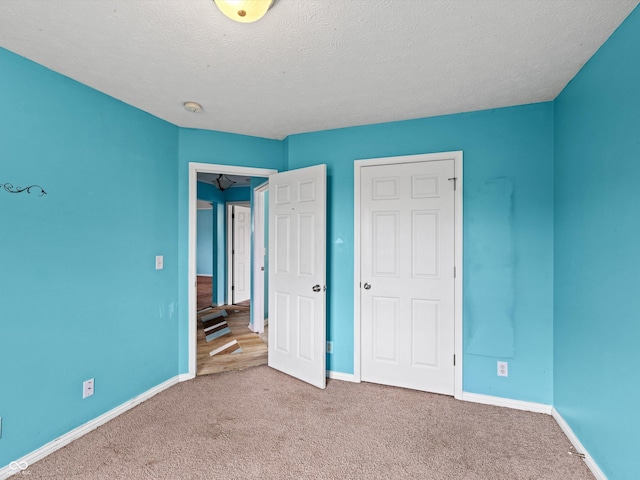 unfurnished bedroom with carpet flooring, a textured ceiling, and baseboards