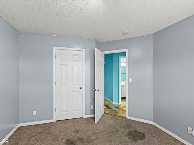 unfurnished bedroom featuring a textured ceiling, carpet flooring, and baseboards