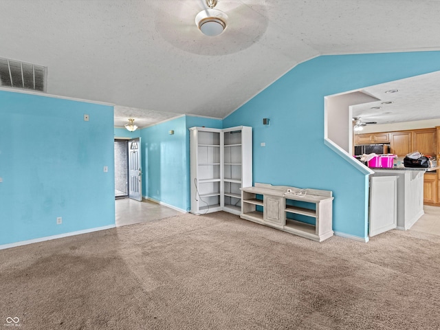 unfurnished living room featuring vaulted ceiling, ceiling fan, visible vents, and light colored carpet