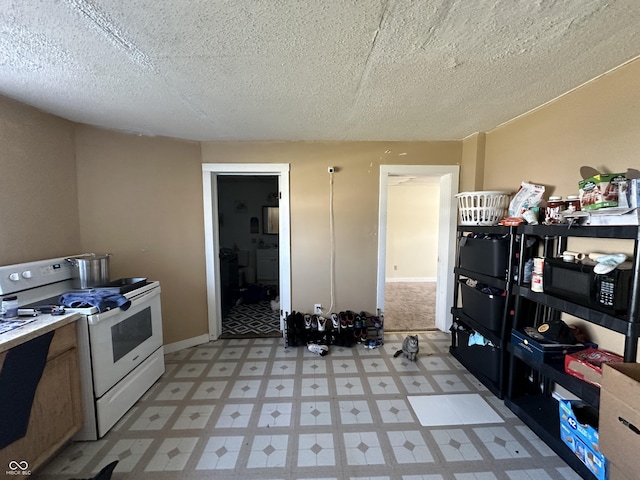 kitchen with white range, washer / clothes dryer, and a textured ceiling