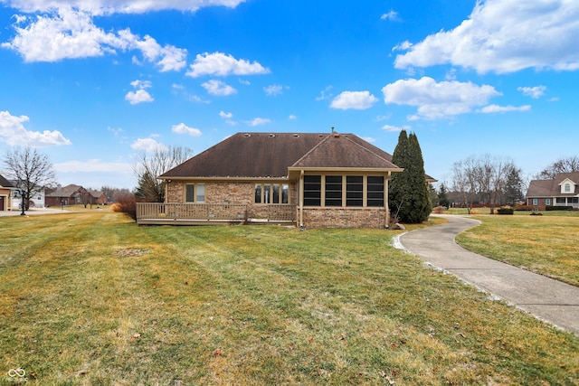 rear view of house featuring a wooden deck and a lawn