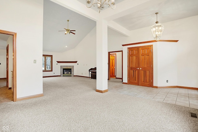 unfurnished living room featuring a tiled fireplace, high vaulted ceiling, light carpet, ceiling fan with notable chandelier, and beamed ceiling