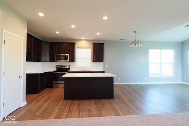 kitchen with appliances with stainless steel finishes, a kitchen island, tasteful backsplash, and sink