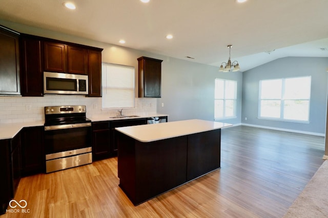 kitchen featuring sink, light wood-type flooring, pendant lighting, a kitchen island, and stainless steel appliances