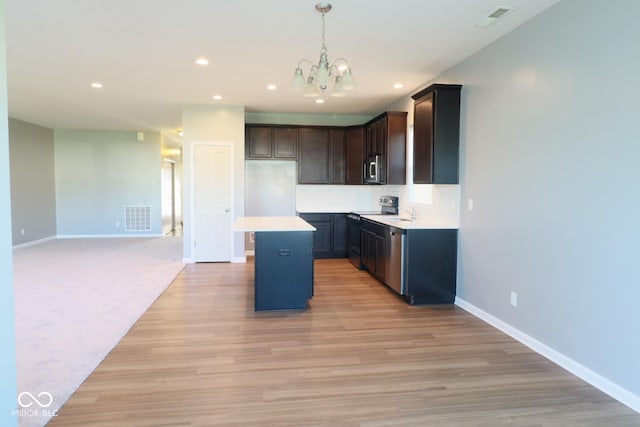 kitchen featuring light hardwood / wood-style flooring, an inviting chandelier, a center island, stainless steel appliances, and hanging light fixtures