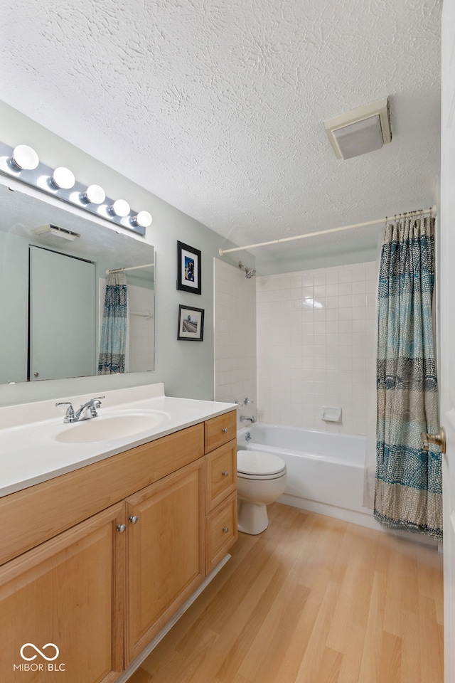 full bathroom featuring shower / tub combo with curtain, hardwood / wood-style flooring, vanity, a textured ceiling, and toilet