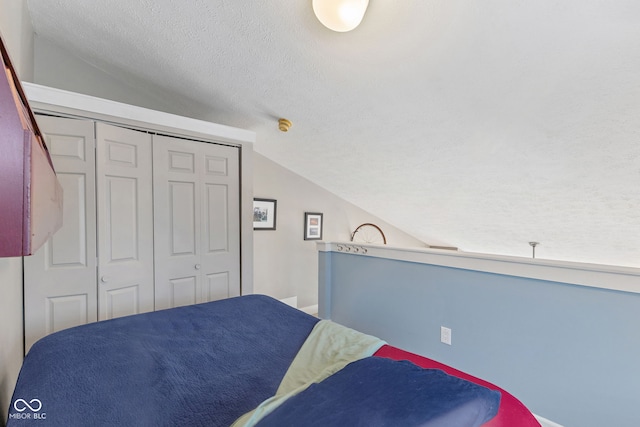 bedroom with lofted ceiling, a textured ceiling, and a closet