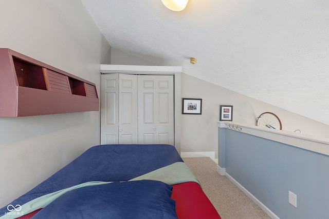 carpeted bedroom with lofted ceiling, a closet, and a textured ceiling