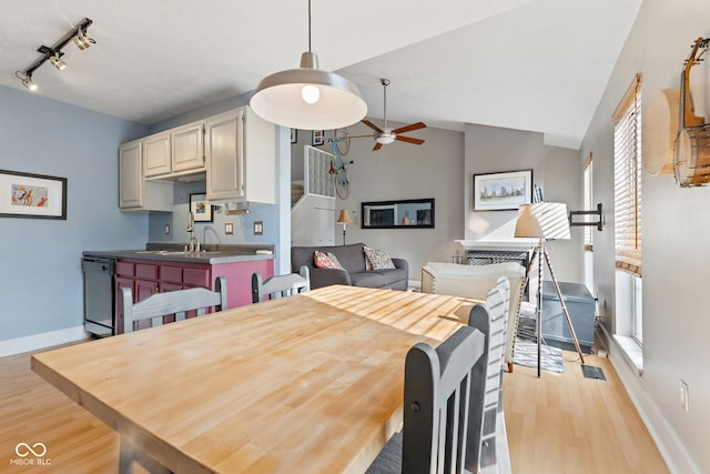 dining area featuring ceiling fan, track lighting, vaulted ceiling, and light wood-type flooring