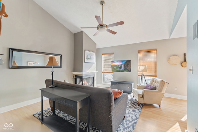 living room with a multi sided fireplace, vaulted ceiling, ceiling fan, and light hardwood / wood-style flooring