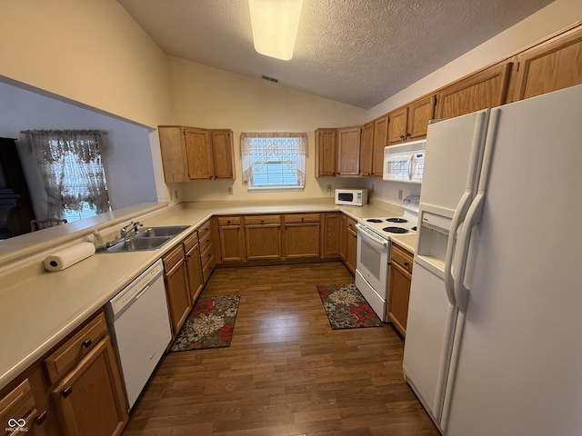 kitchen featuring white appliances, brown cabinets, vaulted ceiling, light countertops, and a sink