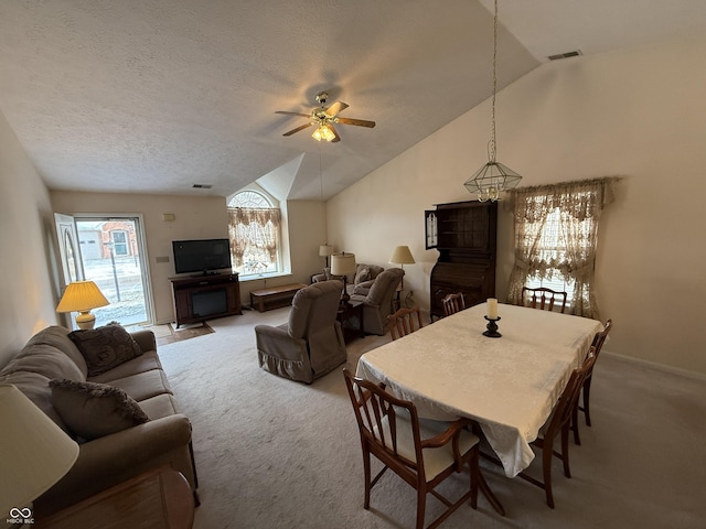 carpeted living room featuring lofted ceiling, a textured ceiling, visible vents, baseboards, and a ceiling fan