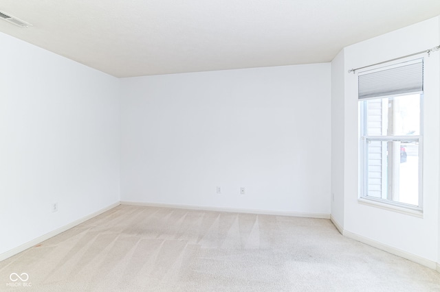 empty room with light carpet, visible vents, and baseboards