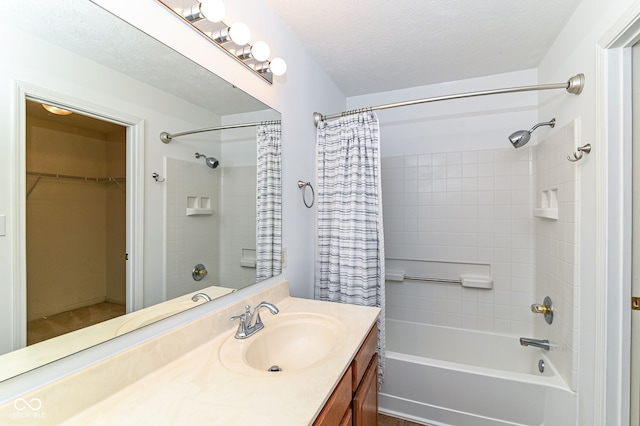 full bathroom with a walk in closet, a textured ceiling, vanity, and shower / bath combo