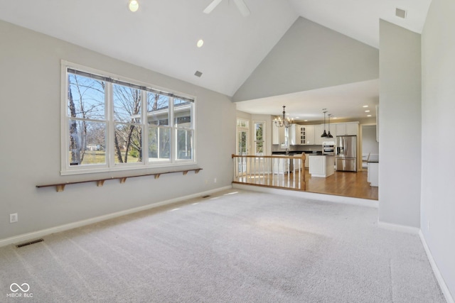 unfurnished living room featuring visible vents, baseboards, high vaulted ceiling, and light colored carpet