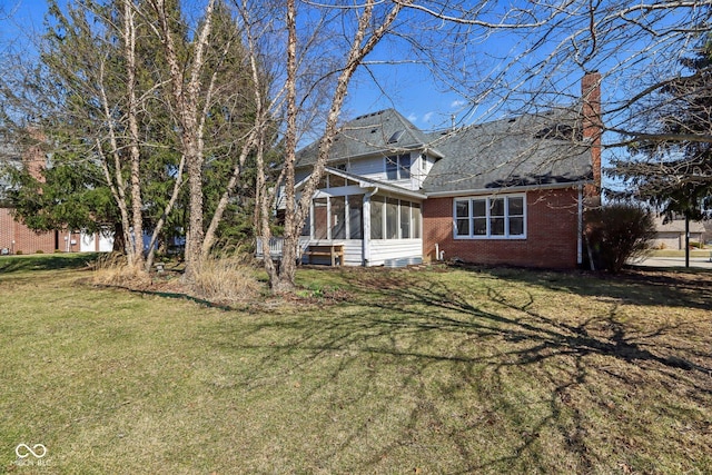 exterior space featuring a front lawn, brick siding, a sunroom, and a chimney