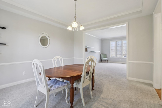 carpeted dining space with a tray ceiling, baseboards, and ornamental molding