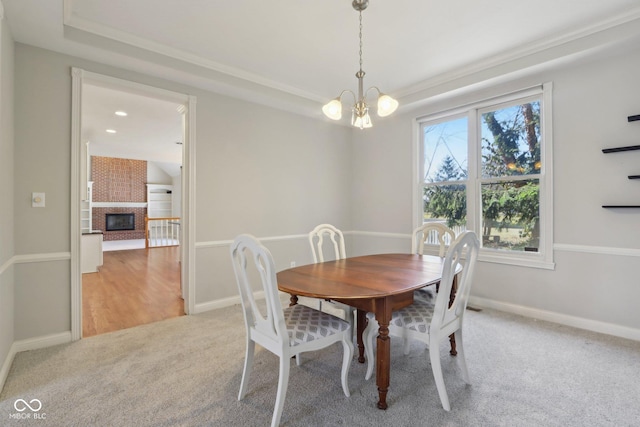 carpeted dining space featuring a notable chandelier, a brick fireplace, and baseboards